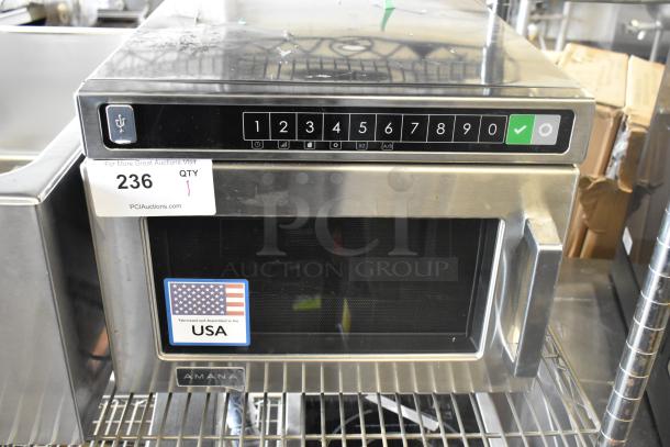 Amana HDC212 Stainless Steel Microwave, new condition, dented. 208/240V, 1 Phase. Auction tag 236; made in USA label visible.