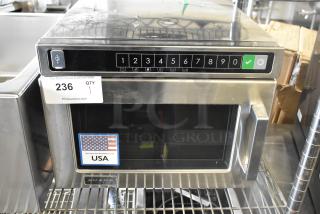 Amana HDC212 Stainless Steel Microwave, new condition, dented. 208/240V, 1 Phase. Auction tag 236; made in USA label visible.