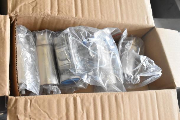 Box of new scratch and dent items, including muffin baking pans and metal legs, in sealed plastic bags.