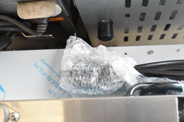 Brand new Avantco 177PG400 stainless steel dual panini grill, sealed in bubble wrap, with visible power cord.