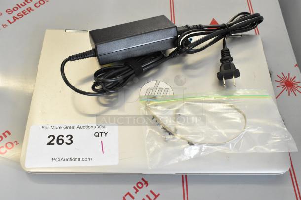HP m1-u001dx laptop with charger, shown with power cable. Auction label: "263 QTY". Visible HP logo on case.