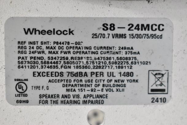 Wheelock S8-24MCC speaker enclosure label, rated at 25/70.7 VRMS, exceeds 75dBA, UL listed, suitable for hearing impaired.