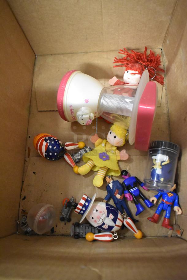 Cardboard box with assorted items: Hello Kitty night light, dolls, figurines, and toys in mixed condition.