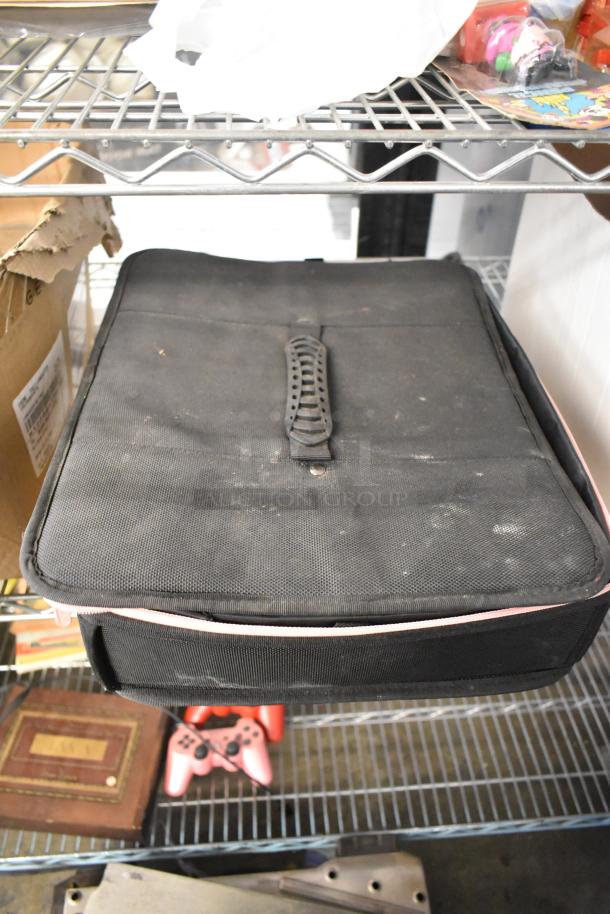 Various items including a worn black storage case, ceramic containers, state plates, and a pink ring pool on metal shelves.