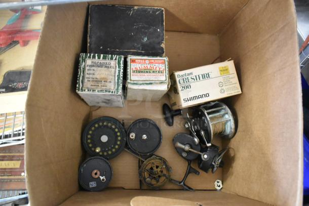 Box of vintage fishing reels, including Sumart and Shimano models, in original packaging. Various condition.