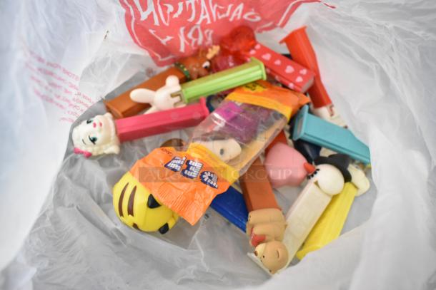 Assorted Pez dispensers and toys in plastic bag, including character-themed items and various small figurines.