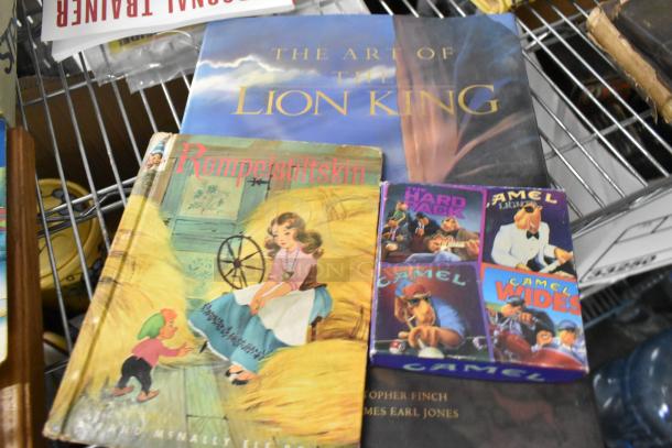 Tier lot featuring "The Art of The Lion King" book, "Rumpelstiltskin" book, and Camel cigarette pack.