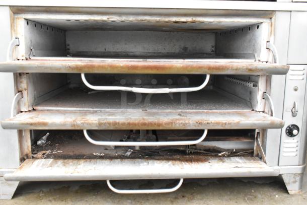 Blodgett stainless steel commercial gas-powered 2-deck pizza oven. Visible wear, sturdy handles, manual controls on side.