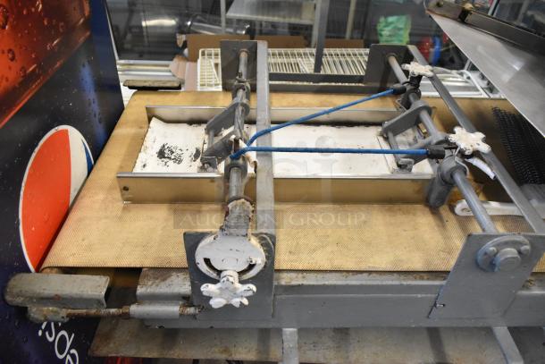 Metal commercial floor-style dough sheeter in used condition, showcasing manual adjustment handles and conveyor belt, ideal for bakeries.