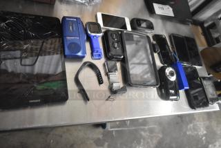 Basket with 22 electronic items including phones, tablets, Olympus Pearlcorder S702, Vivitar camera; some damaged.