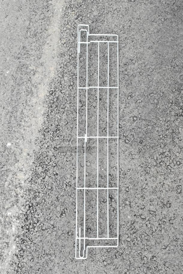 A vertical metal frame laying on a textured surface.