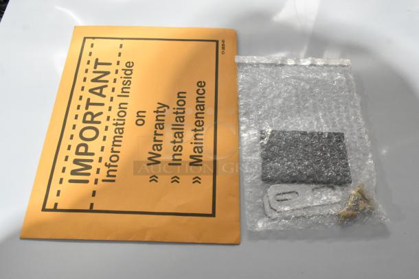 Orange envelope labeled "Important: Information Inside on Warranty, Installation, Maintenance" next to bubble-wrapped items.