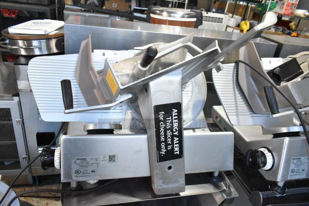 Bizerba SE 12 US commercial meat slicer with blade sharpener, stainless steel, on equipment stand. Includes allergy alert label.