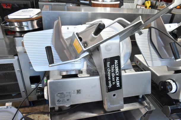 Bizerba SE 12 US commercial meat slicer, stainless steel, with blade sharpener, on equipment stand, 120V, 1 Phase. Sign: "Allergy Alert."