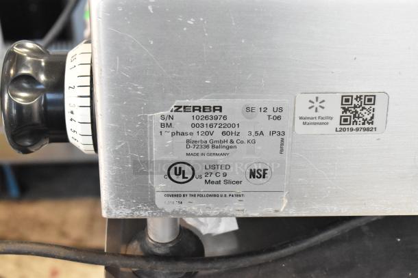 Bizerba SE 12 US commercial meat slicer with blade sharpener and stainless steel stand. 120V, 1 phase. Labels show model details and certifications.