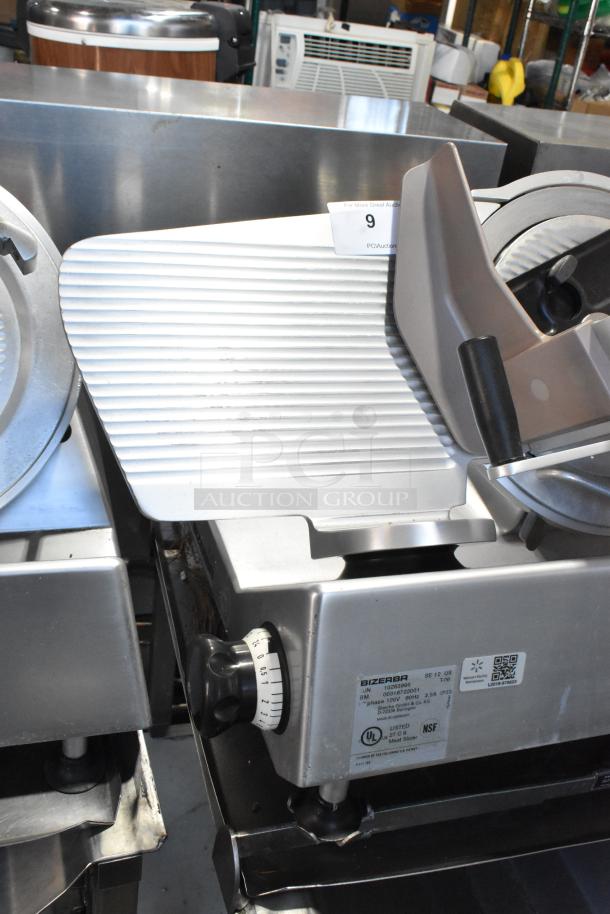 Bizerba SE 12 US metal commercial meat slicer with blade sharpener, mounted on stainless steel stand. 120V, 1 phase.