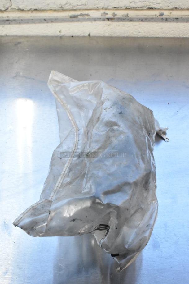 A plastic-wrapped item on a metal surface, not showing the Bizerba SE 12 US meat slicer described.塑料包裹的物品放在金属表面上，未显示描述的Bizerba SE 12 US切片机。