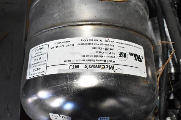 Stainless steel tank with a label indicating 40 PSI factory precharge and NSF certification, part of the water booster system.