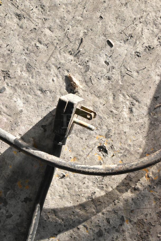 Alt text: Close-up of a power plug on concrete, belonging to a True T-23F stainless steel freezer, 115 volts, 1 phase.