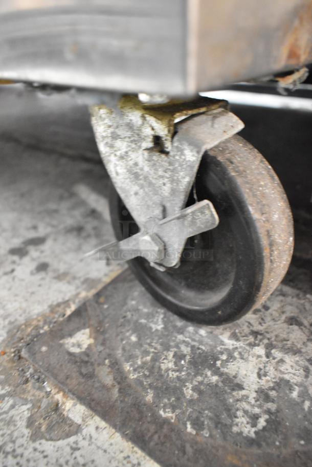 Traulsen AHT132WUT-FHS cooler caster, sturdy black wheel with locking mechanism, visible wear, part of commercial appliance.