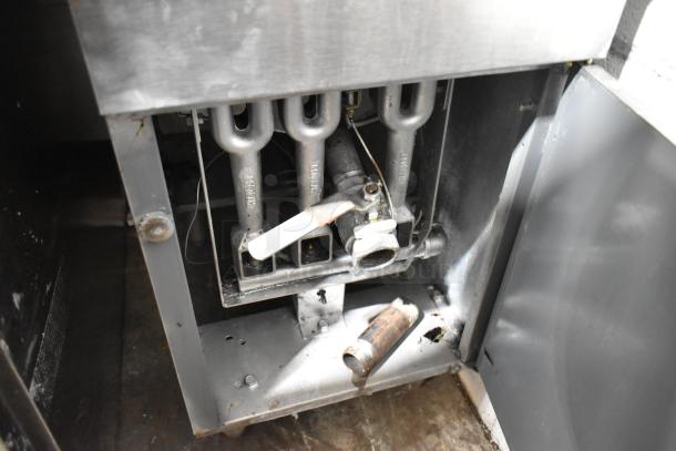 Stainless steel commercial floor deep fat fryer with two metal fry baskets, showing internal burner components.