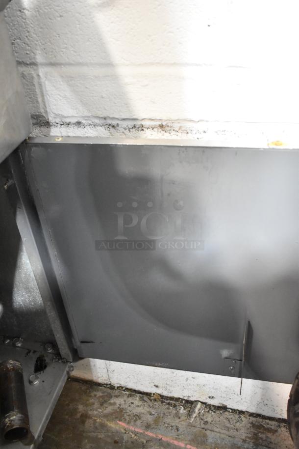 Stainless steel commercial deep fat fryer with 2 metal fry baskets, floor style, visible wear on exterior panel.