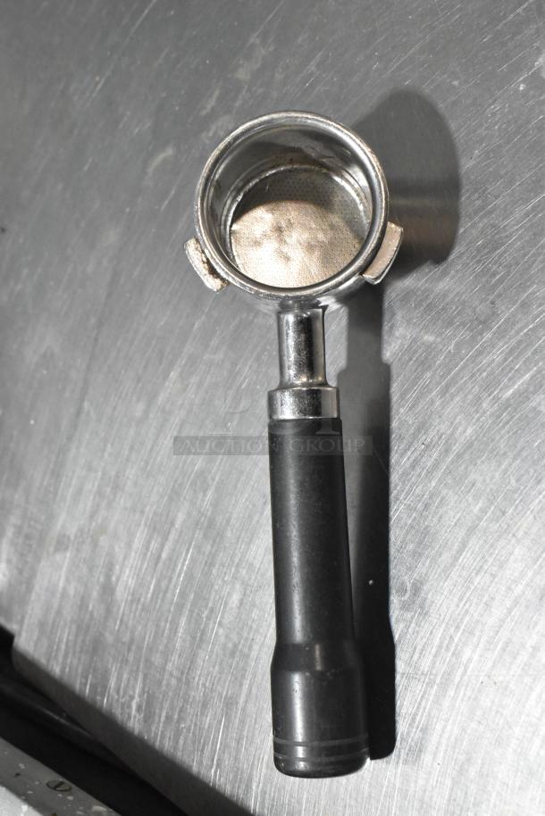 La Spaziale portafilter on stainless steel surface; essential for espresso machine use. Good condition, sturdy black handle.