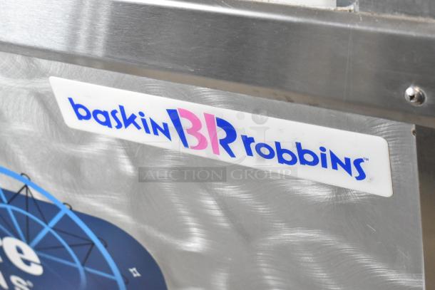 Metal commercial ice cream dipping cabinet with bucket collars, featuring Baskin Robbins branding and stainless steel finish.