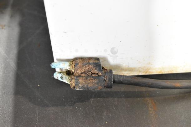 Close-up of a damaged power plug on a Robot Coupe R2 food processor, showing corrosion and rust on the prongs.