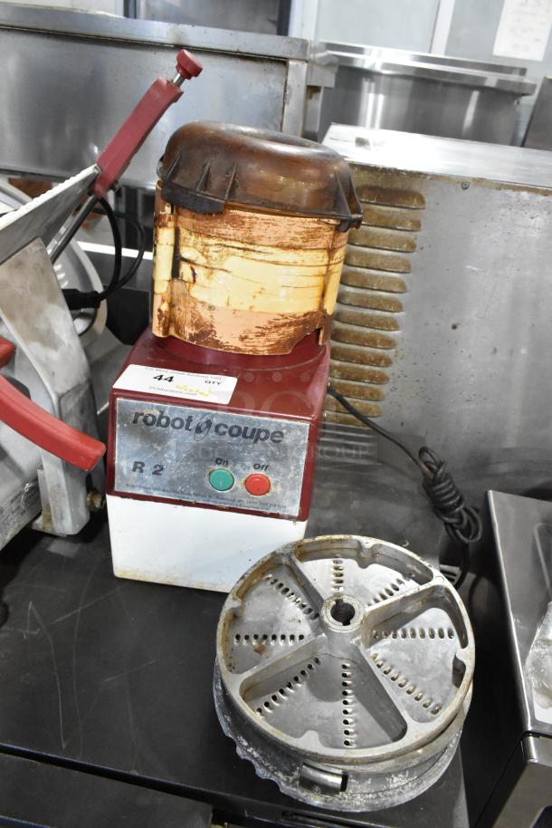 Robot Coupe R2 food processor with metal base, bowl, lid, 2 grating blades, slicing blade; used condition, 120V, 1 phase.