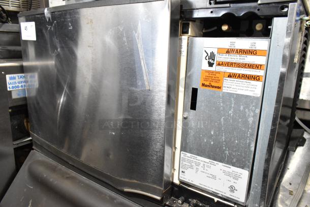 Manitowoc SD0302A stainless steel commercial ice head on bin. Shows some surface wear. 115 volts, 1 phase. Warning labels visible.