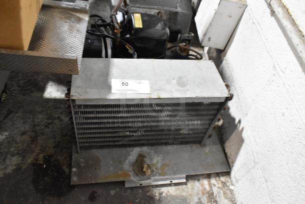 Commercial compressor in used condition, features metal casing, visible piping, and labeled auction tag indicating item 50.
