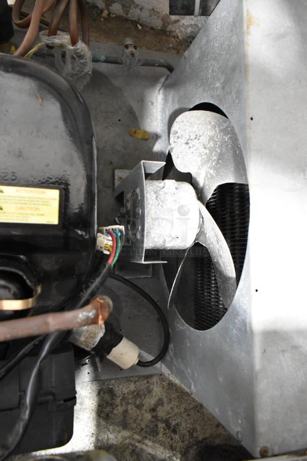 Commercial compressor with metal housing and fan. Visible wires and connectors indicating operational components. Moderate wear.