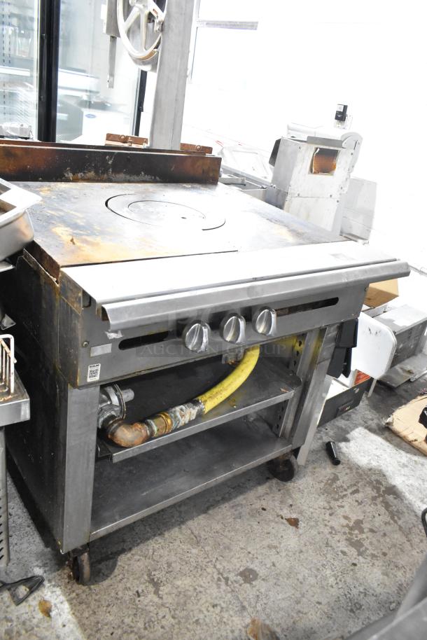 Stainless steel commercial single burner French top range with two under shelves, gas powered, on casters, visible wear.