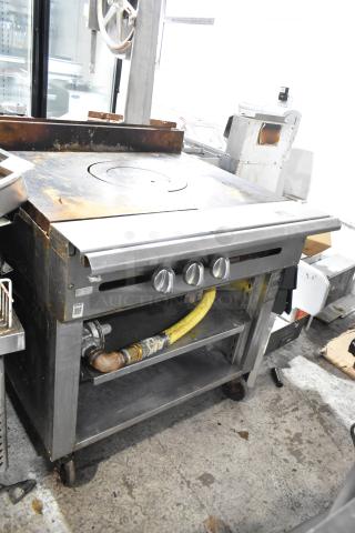 Stainless steel commercial single burner French top range with two under shelves, gas powered, on casters, visible wear.