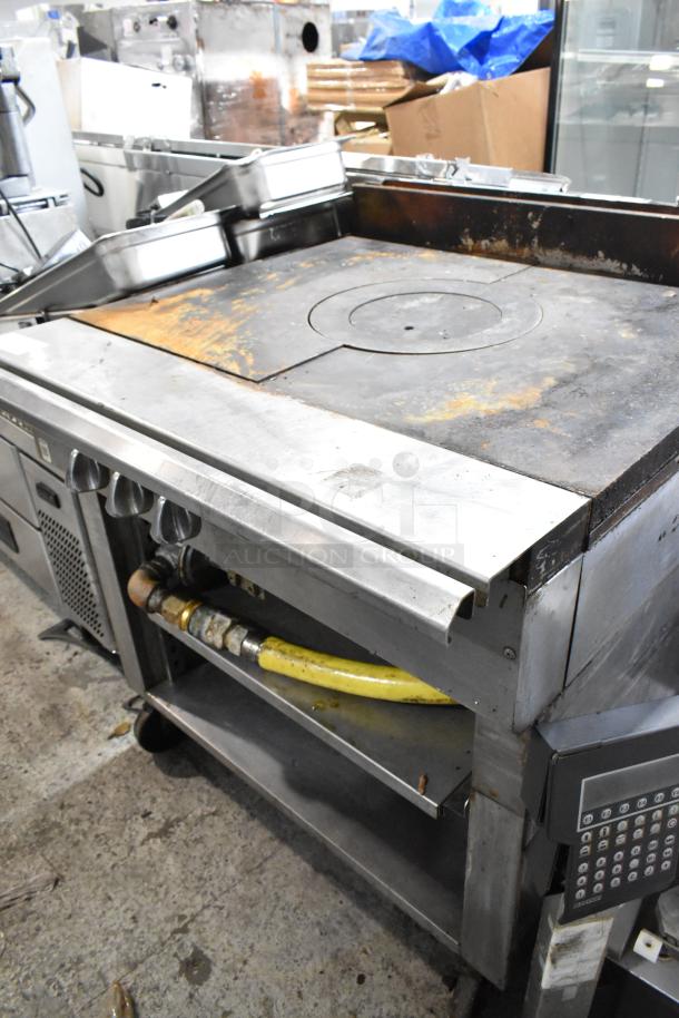 Stainless steel commercial gas burner with French top, two under shelves, on casters. Features worn surface, durable construction.