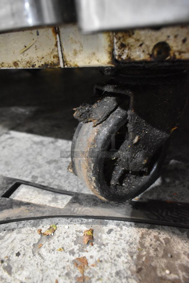 Stainless Steel Commercial Chef Base with four drawers on worn commercial caster. 115 Volts, 1 Phase. Signs of use shown on caster.