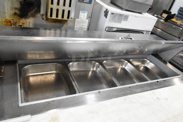 Beverage Air SPE48HC-12C stainless steel prep table with four stainless bins, visible markings, on commercial casters.