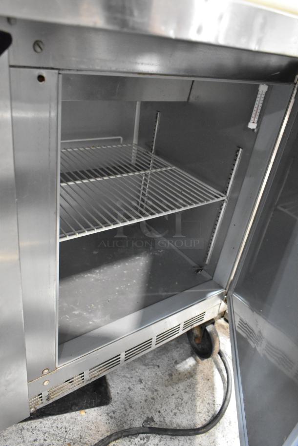 Beverage Air SPE48HC-12C stainless steel prep table. Open door showing interior shelves. Commercial casters visible.