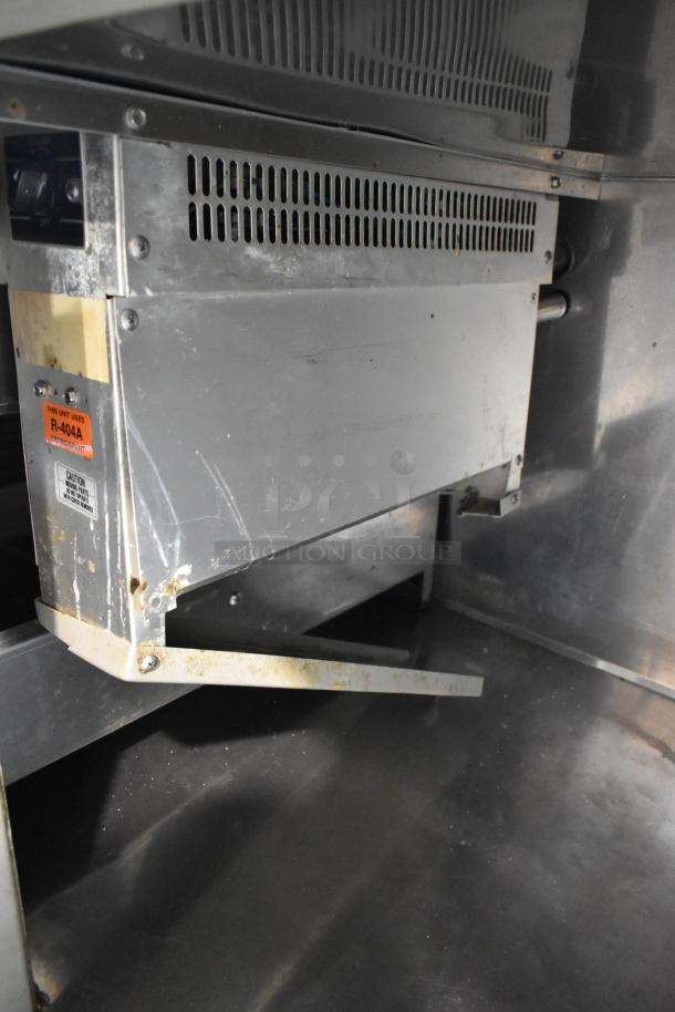 Randell 51395PR stainless steel pizza prep table interior, showing commercial casters and cooling unit with R-404A refrigerant label.