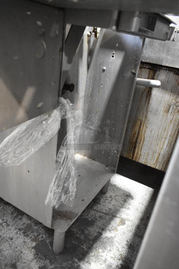 Metal commercial floor-style meat saw, shown in well-used condition with visible rust spots and plastic sheet attached.