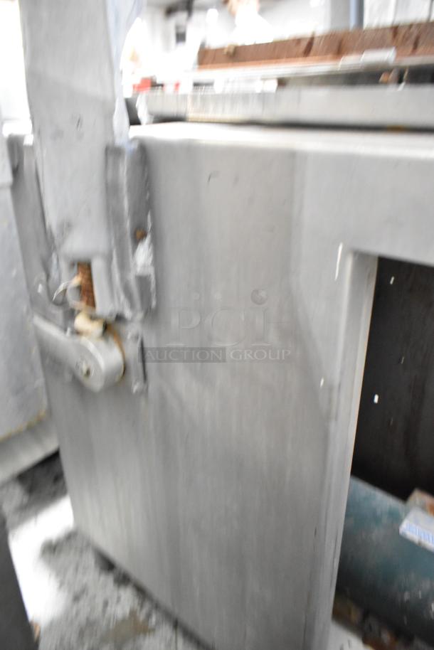 Metal commercial floor-style meat saw, industrial-grade, robust construction, visible wear, suitable for heavy-duty use.