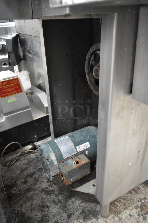 Metal commercial floor-style meat saw with visible rust and wear, featuring a motor labeled "Dangerous," indicating caution.