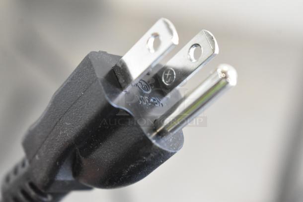 Close-up of a power plug connected to a Bunn MyCafe stainless steel commercial espresso machine.