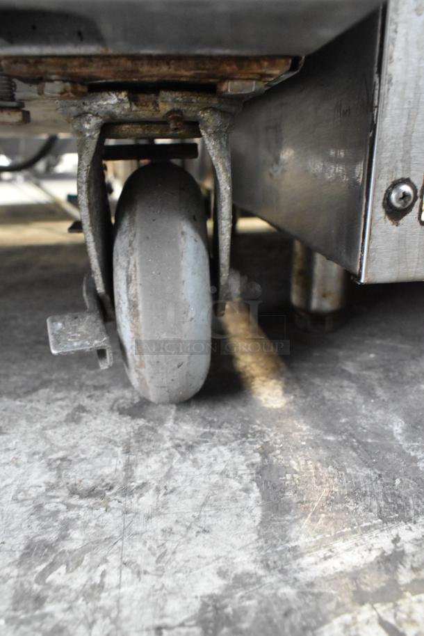 L&J NY stainless steel convection oven caster, with visible wear, attached to sturdy base.