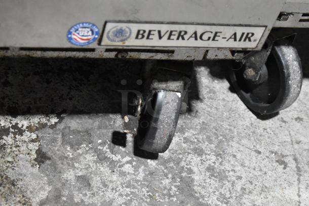 Beverage Air SPE48-18M-HMP stainless steel prep table on commercial casters, features visible wear. Tags indicate manufacturer.