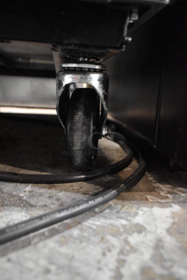 Close-up of a caster wheel on a 2024 True T-23-HC cooler, showing the sturdy metal and rubber design for mobility.