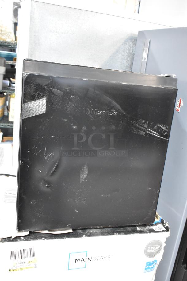 Two mini coolers, Hisense B95LE and Mainstays, 115 volts, 1 phase. Visible wear. Mainstays box shows 1-year warranty.