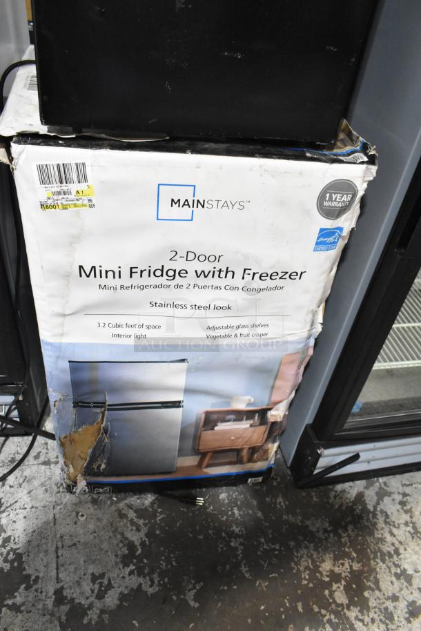 Two mini coolers: Hisense B95LE and Mainstays, 115 volts, 1 phase. Mainstays box damaged, features 2-door design.