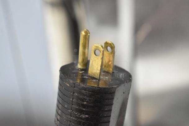 Black electrical plug with three exposed brass prongs from JBT Fresh N Squeeze Citrus Juicer.